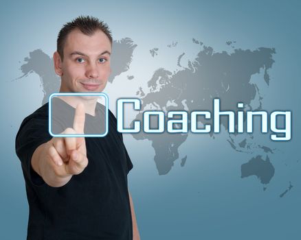 Young man press digital Coaching button on interface in front of him