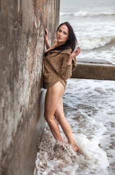 Seminude woman near concrete constructions on the sea shore