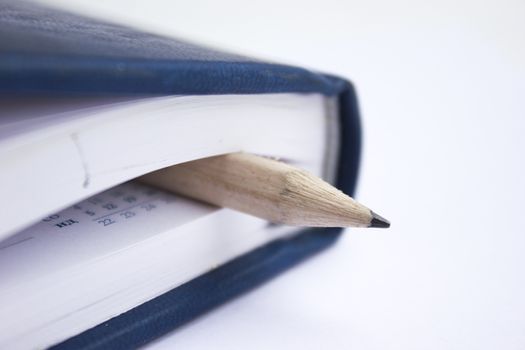 Pencil in a composition with a blank book with hardcovers.