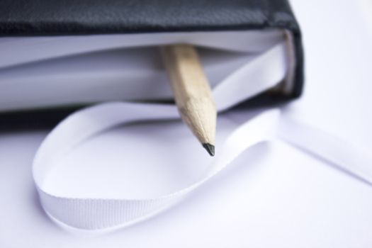 Pencil in a composition with a blank book with hardcovers.