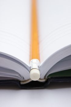 Pencil in a composition with a blank book with hardcovers.