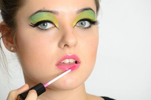 Portrait of young Polish female. Teenage girl with colorful makeup using lip gloss on her lips.