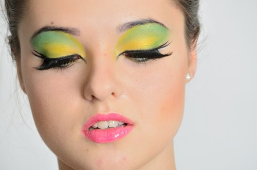 Young female model with colorful makeup. Face closeup portrait photo of teenager. 