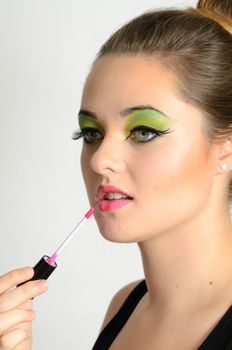 Portrait of young Polish female. Teenage girl with colorful makeup using lip gloss on her lips.