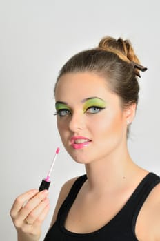 Portrait of young Polish female. Teenage girl with colorful makeup using lip gloss on her lips.