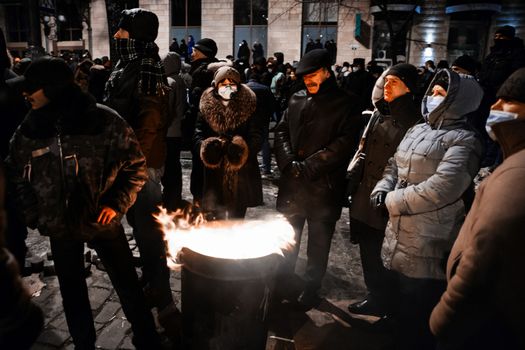 KIEV, UKRAINE - January 20, 2014: Mass anti-government protests in the center of the Ukrainian capital Kiev. Members of the Popular Resistance basking near the fire  on Hrushevskoho St.
