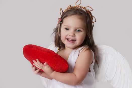 Happy cupid girl holds plush heart isolated on white