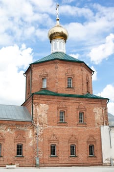 Brick red orthodox church with one golden dome
