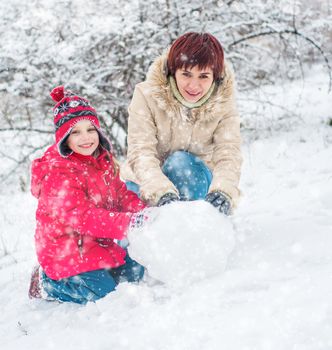 Mom and daughter molded ball of snow for a snowman