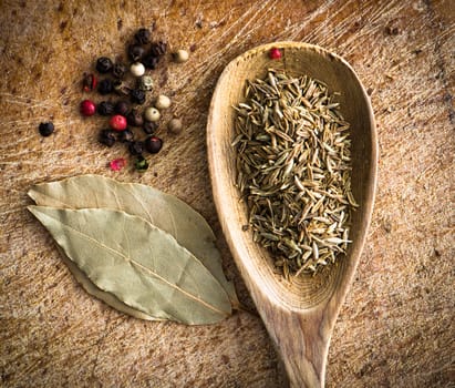 spices in a wooden spoon with laurel leaves on a cutting board