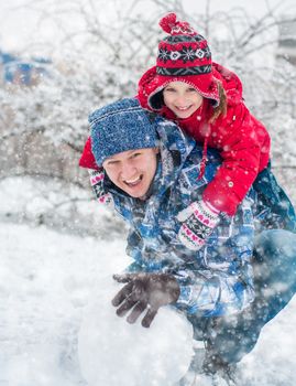 Father and daughter molded ball of snow for a snowman