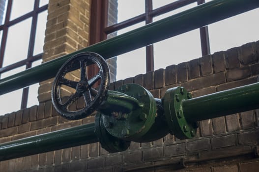green manual valve in green metal tube in industrial building