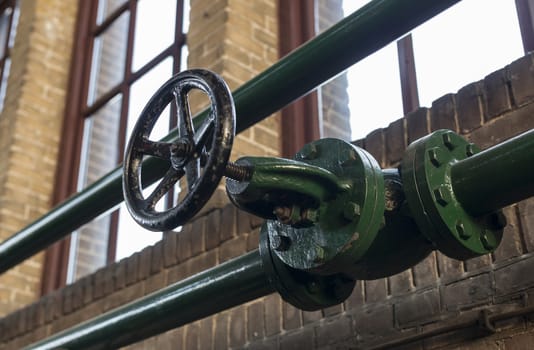 green manual valve in green metal tube in industrial building