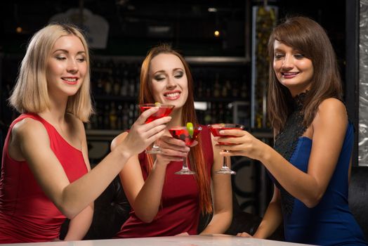 three girls raised their glasses in a nightclub, have fun with friends