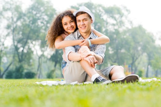 romantic couple lying on the grass in the summer park, spending time with loved ones