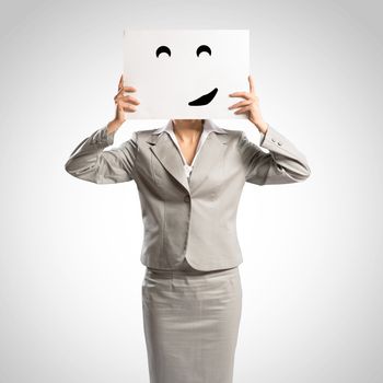 business woman holding a poster with a painted face on it instead of a face, the concept of duplicity in business