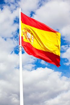 Flag of Spain over blue sky moving in wind