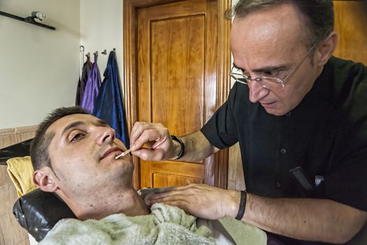 barber treats small wounds after shaving with razor in a barber's shop, Sabiote, Jaen province, Andalucia, Spain
