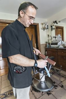 Barber sharpens razor old-fashioned in a barber's shop, Sabiote, Jaen province, Andalucia, Spain