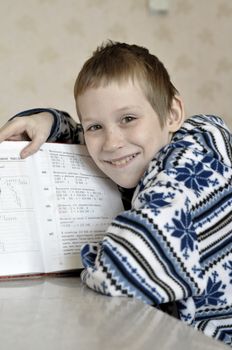 The 10-year-old boy sits with the textbook, doing homework