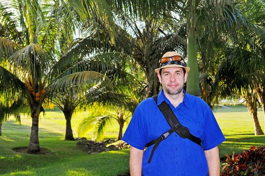 White tourist man posing in front of tropical palm trees