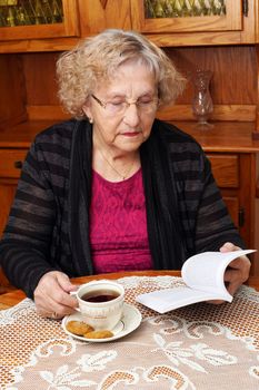 Senior woman enjoying afternoon tea and reading a book at home