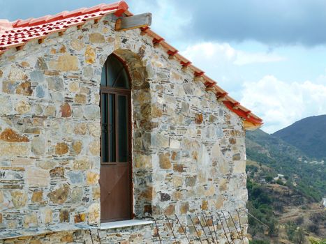 Old stone house in Greece with wood door and red clay roof