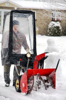 Man uisng snowblower in his home entryway during a winter blizzard