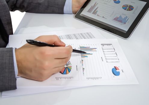 Businessman reviewing chart documents with digital tablet computer in the workplace