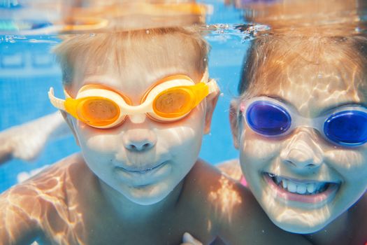 Close-up underwater portrait of the two cute smiling kids