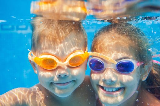 Close-up underwater portrait of the two cute smiling kids