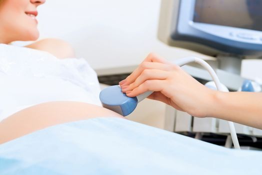 close-up of hands and abdominal ultrasound scanner for pregnant women