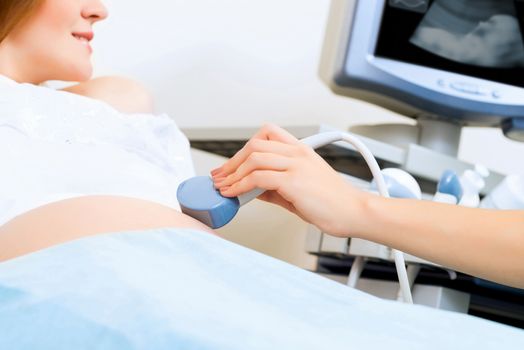 close-up of hands and abdominal ultrasound scanner for pregnant women