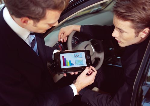 Man buying a car in dealership sitting in his new auto, the salesman talking to him and explaining details on laptop