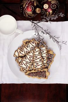 Plate of Christmas trees with cup of milk and beautiful ornaments in the background. 