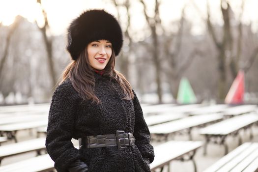 Business woman wearing fur hat, coat and gloves in park