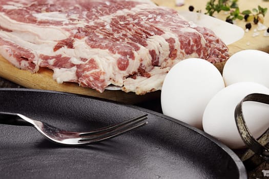 Uncooked beef bacon with fresh eggs and herbs. 