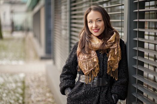 Young pretty lady is standing by the louvers and enjoying winter