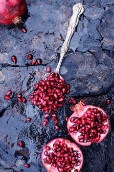 Pomegranate seeds in an antique silver spoon over a rustic background. 