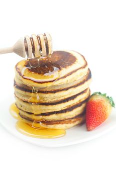 Pancakes, honey, strawberry and stick to honey isolated on white