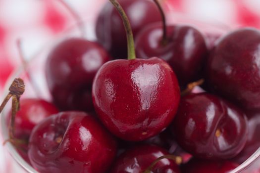 Cherries in a glass bowl on checkered fabric