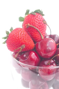 Cherries and strawberry in a glass bowl isolated on white