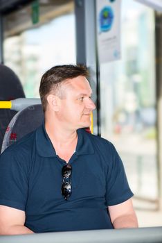 man traveling by bus and looking away in window