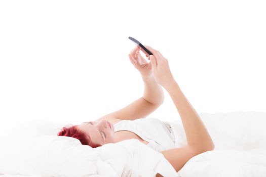 young redhead woman texting with her smartphone in bed