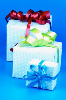 Heap of Three Gift Boxes with Ribbons and Bows in a Row isolated on Blue background