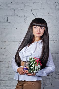 Attractive young brunette girl holding a bouquet of flowers