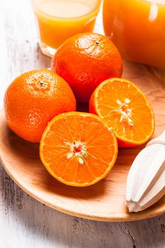 The preparation for tangerine juice for breakfast. Wooden  citrus reamer with fruits.