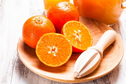 The preparation for tangerine juice for breakfast. Wooden  citrus reamer with fruits.