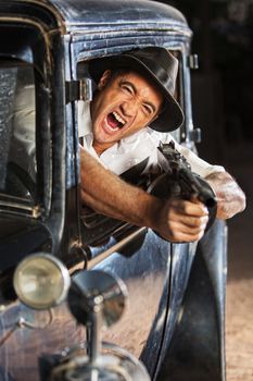 Yelling man firing submachine gun from vintage 1920s car