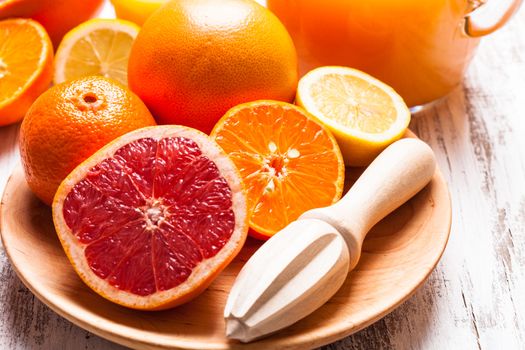 The preparation for citrus juice for breakfast. Wooden  citrus reamer with fruits.